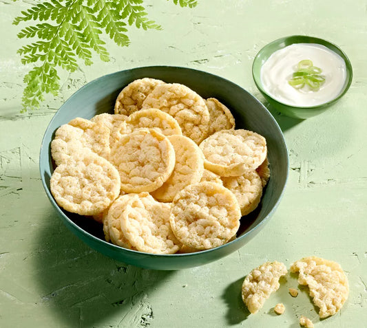 Bowl of Herbalife Protein Chips Sour Cream Flavour with a small dish of sour cream on a green background